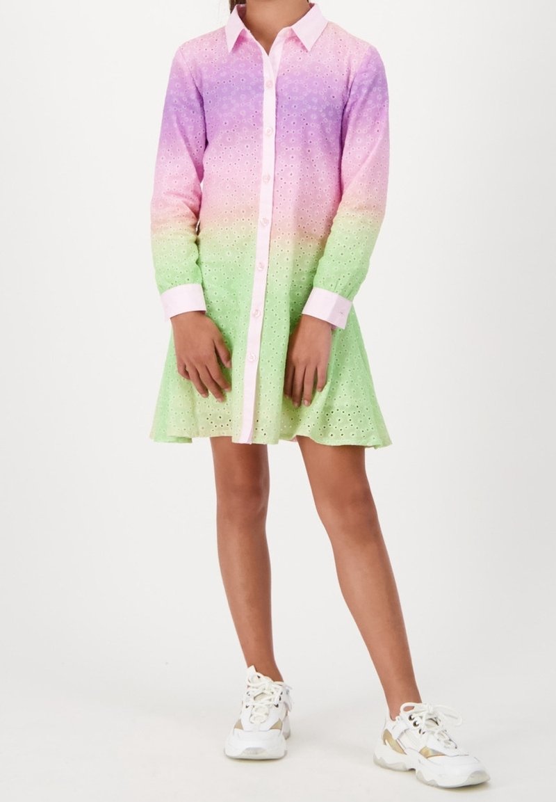 Enfant portant une robe à manches longues boutonnée avec un tissu ajouré en dégradé de rose, violet et vert, associée à des baskets blanches.