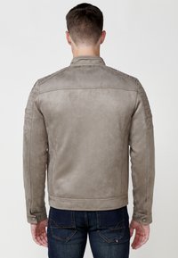 Jachetă din suede gri cu accente ribbed pe umeri și manșete cu nasturi, având o textură netedă și o siluetă ajustată. Detalii de cusătură vizibile.