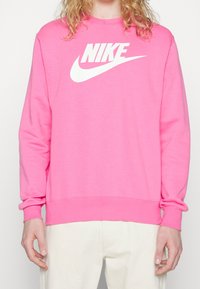 Rosa Nike-tröja med en stor vit logotyp. Långa ärmar, rund halsringning och ribbade ärmslut och nederkant. Mjuk tygkvalitet.