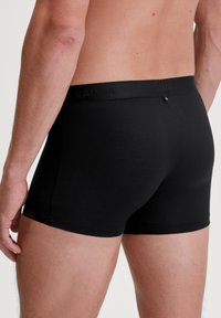 Zwarte boxershorts gemaakt van zacht, rekbaar materiaal. Beschikt over een gladde tailleband met een subtiel logo en een strakke pasvorm rond de dijen.