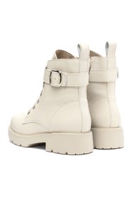 Botas de tobillo blancas de cuero con un acabado texturizado, punta redonda, diseño de cordones frontal y correa ajustable con hebilla en el tobillo.