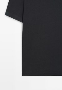 T-shirt noir à manches courtes et col rond, présenté de la moitié de la manche à l'ourlet sur fond blanc.