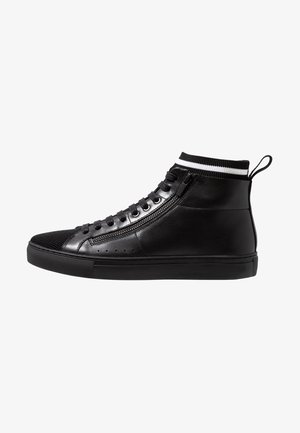 Zwarte hoge sneaker met zijrits, zwarte veters, gebreide kraag met witte streep en aantreklus bij de hiel.