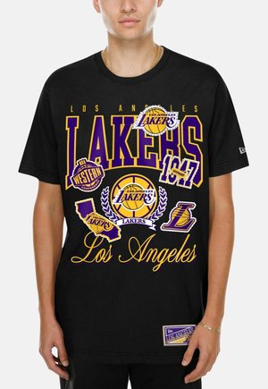 Personne portant un T-shirt noir des Los Angeles Lakers avec plusieurs logos de l'équipe, du texte et des graphiques de basket en violet et jaune.