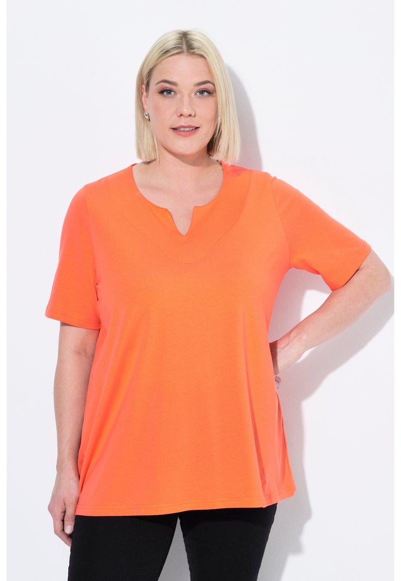 T-shirt arancione a maniche corte con scollatura ampia, realizzato in tessuto morbido, caratterizzato da una vestibilità ampia e dettagli di cucitura discreti.