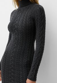 Robe à col roulé en maille torsadée, mélange de laine gris foncé. Présente un col côtelé et un corps texturé avec des manches longues. Finition lisse sur l'ensemble.