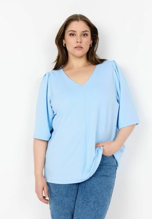 Light blue V-neck blouse with short sleeves and gathered shoulder details, paired with denim jeans. Smooth texture and relaxed fit.