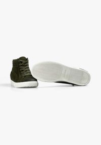 Zapatillas altas de ante verde con suela de goma blanca, que presentan un acabado texturizado y costuras detalladas en los lados y los cordones.