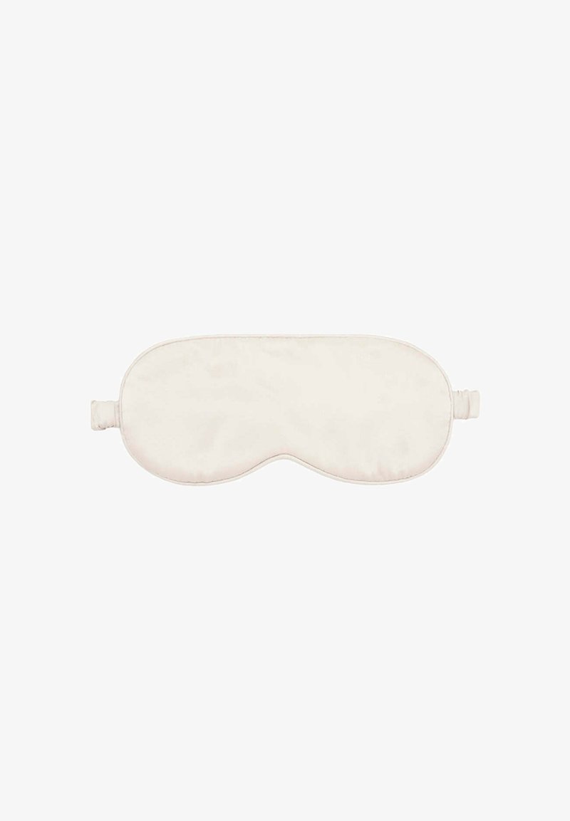 Masque de sommeil beige doux avec une bande élastique conçue pour couvrir les yeux afin de bloquer la lumière pendant le repos.