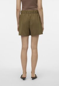 Brune elastiske shorts med løs passform, laget av myk stoff; glatt tekstur, midt på låret lengde, og ingen synlige mønstre eller tilbehør.