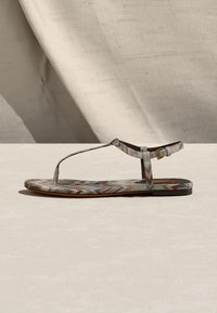 Πλατφόρμα σανδάλι με υφασμάτινο σχέδιο, σχεδιασμό Τ-λουριού και μικρή χρυσή αγκράφα στο λουράκι αστραγάλου, σε ουδέτερο φόντο.
