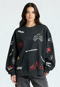 Felpa nera con grafiche, inclusi testi e simboli in bianco, rosso, giallo e verde, caratterizzata da una vestibilità ampia e polsini a costine.