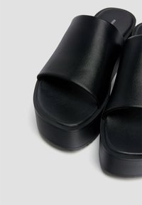 Sandales à plateforme noires avec un dessus en simili cuir lisse, un design à bout ouvert et une semelle épaisse et profilée pour le confort.