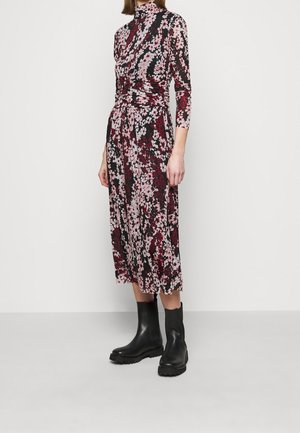 Blumenkleid in mittellanger Form mit hochgeschlossenem Kragen, schwarz als Grundfarbe, verziert mit rosa und burgunderfarbenen Blumen und einer taillierten Passform. Kombiniert mit schwarzen Ankle Boots.