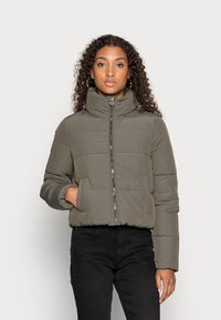 Veste matelassée olive verte avec col montant, fermeture éclair avant et poches latérales. Présente des coutures horizontales et des poignets élastiques.