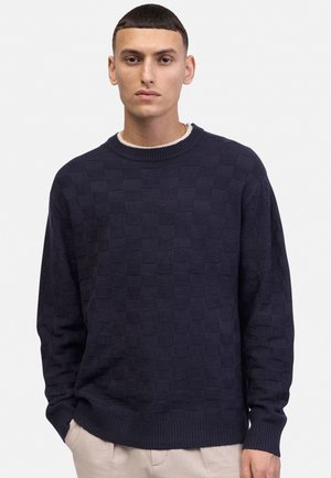 Pull marin avec un motif à carreaux 3D, col rond et poignets côtelés. Fabriqué en tissu texturé, offrant une coupe décontractée et une finition douce.
