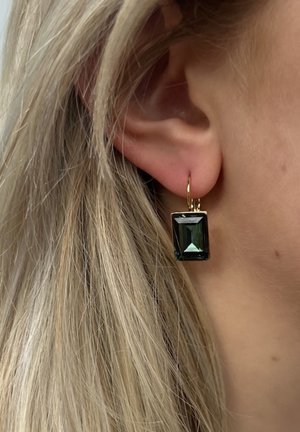 Boucles d'oreilles en forme de créoles dorées avec un pendentif en cristal vert taillé en émeraude, mettant en valeur des facettes et une finition polie.