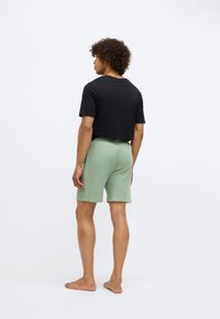 Un tricou negru și șorturi verde-mint, realizate dintr-un material moale. Șorturile au un design simplu, cu un elastic confortabil.