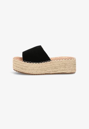 Sandalia tipo slide negra con puntera abierta, suela plataforma beige gruesa tejida y detalle de costura en ángulo a lo largo del borde.