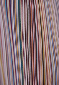 Nærbillede af tæt vævet stof med lodrette striber i forskellige farver, herunder rød, blå, gul, sort og hvid.