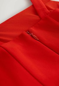 Rotes Kleid aus Stoff mit glatter Textur und einem Reißverschlussdetail an der Taille. Das Kleid hat ein schlichtes, sauberes Design und verstellbare Träger.