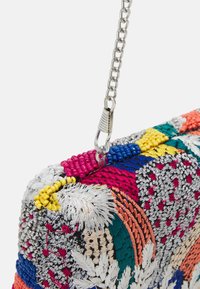 Borsa a pochette colorata intrecciata con ricami intricati. Presenta una tracolla in argento, texture miste e motivi vibranti in varie tonalità.