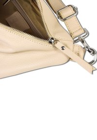 Beige leren handtas met een gestructureerde oppervlakte, ritsafsluiting en zilverkleurige hardware. Verstelbare schouderband bevestigd met een drukknoop en metalen ring.