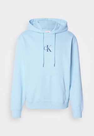 Sweatshirt azul claro com capuz, feito de uma mistura suave de algodão, apresentando um bolso canguru na frente e um logótipo impresso da Calvin Klein no peito.