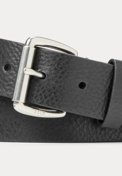 Fekete texturált bőrvérű öv ezüstszínű, téglalap alakú csattal, amelyen a "POLO" felirat látható, és egy övhurkúval fehér háttéren.