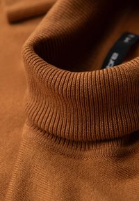 Brauner Strickpullover mit Stehkragen. Glatte Textur mit feinen Nähdetails und einem sichtbaren Markenlabel im Nacken.