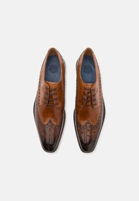 Scarpe da dress in pelle marrone con design brogue, caratterizzate da un bordo scallopato, dettagli testurizzati e una punta lucida di colore scuro.