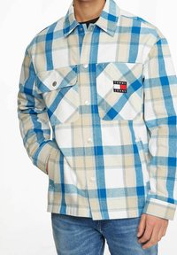 Blå och beige rutiga skjorta i bomull, med två framfickor, krage med knappar och en logotäpp på vänster bröst.