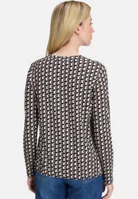 Długi rękaw bluzka z geometrycznym wzorem w przytłumionych odcieniach różu, czerni i kremu, z okrągłym dekoltem i gładką teksturą tkaniny.