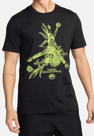 Czarny t-shirt z neonowo żółtą grafiką postaci skaczącej z piłką, otoczonej kwiatowymi elementami i napisem „Maison des Champions.”