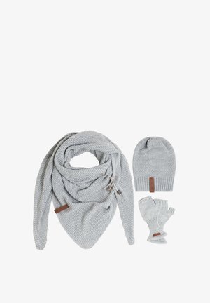 Écharpe en tricot grise avec des pompons sur les côtés, bonnet assorti et gants sans doigts, le tout présentant un motif texturé et des accents en cuir.