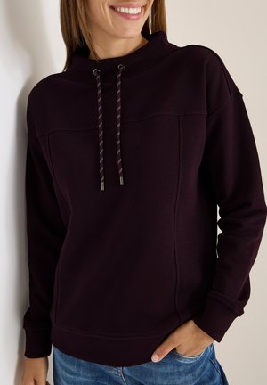 Mørk lilla pullover hoodie med høj hals, justerbar snor og ribbede manchetter. Stoffet ser blødt og struktureret ud.