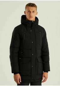 Schwarze Wattierte Jacke mit Kapuze, Reißverschluss-Taschen, Druckknöpfen und einem gesteppten Muster. Das Innenfutter ist für Wärme und Isolierung ausgelegt.