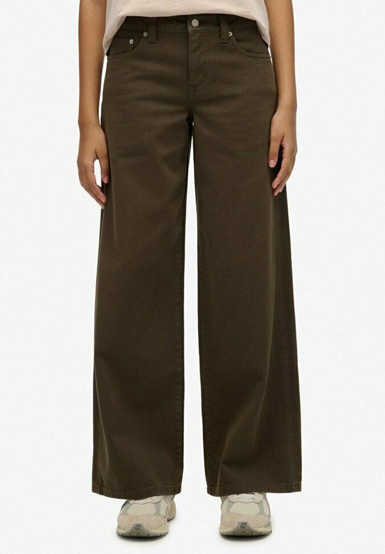 Pantalones de pierna ancha color verde oliva, hechos de algodón, con una cintura alta, bolsillos frontales y una textura suave. Lleva puestos unos zapatillas grises.
