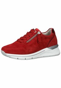 Zapatilla de ante rojo con puntera redonda, suela blanca texturizada y un detalle metálico plateado. Presenta cordones y un detalle de cremallera lateral.