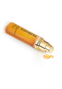 Siero Eisenberg Paris in una bottiglia cilindrica trasparente con pompa dorata. Un liquido ambrato vischioso si versa sulla superficie.