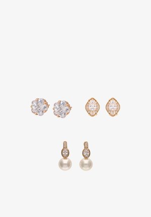 Trzy pary kolczyków na sztyfcie: przejrzyste kryształowe kwiaty, złote geometryczne z przejrzystymi kamieniami oraz złote wiszące z małymi kryształami i perłą.