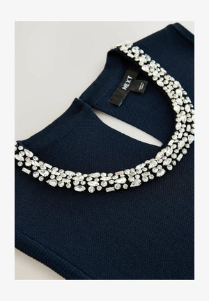 Granatowy sweter z dzianiny z ozdobnym dekoltem, udekorowany przezroczystymi rhinestone'ami w różnych kształtach. Metka z napisem "NEXT".