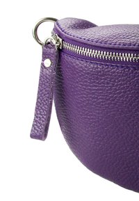 Paarse leren handtas met een gebogen vorm, textuur, zilveren rits en een korte polsband met een drukknoopdetail.