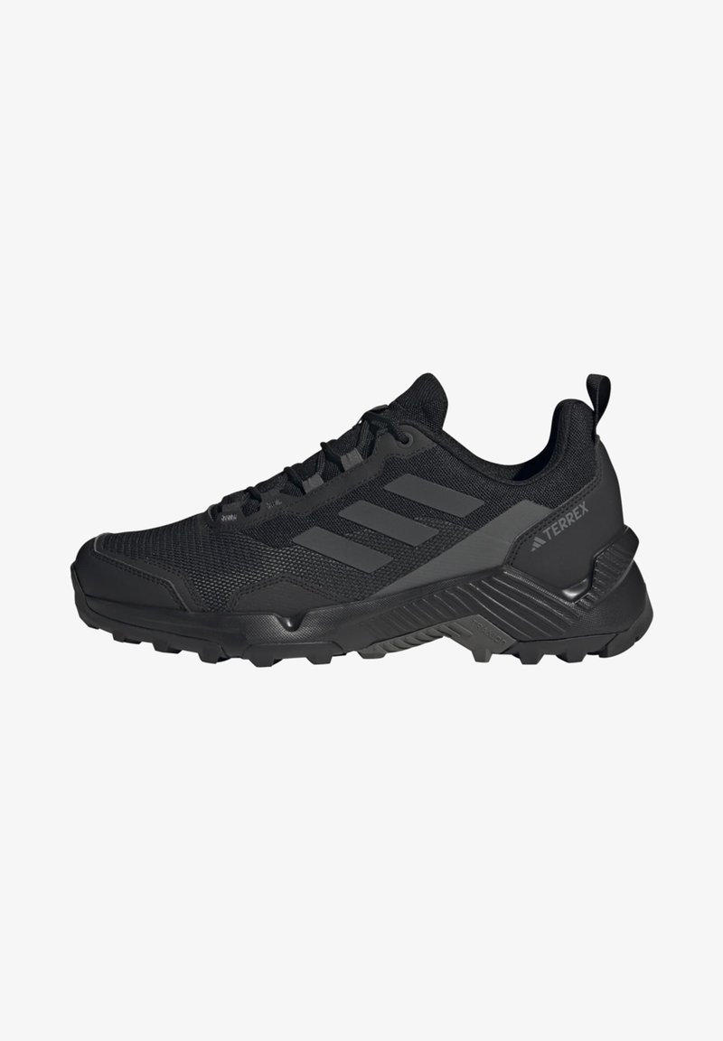 Black hiking shoes with a mesh upper, synthetic overlays, and a sturdy sole with traction patterns. Features three black stripes on the side.