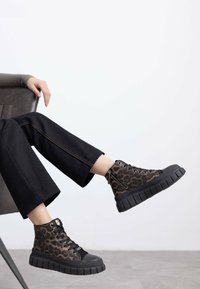 Sneaker alte realizzate in tessuto con stampa animalier, con suole in gomma nera, dotate di lacci e cerniere laterali per una vestibilità facile.