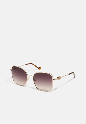 Lunettes de soleil en métal doré avec une forme carrée, verres dégradés violets et embouts de branches teintés marron. Présentent un logo sur la monture.