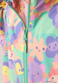 Kolorowa kurtka dziecięca z zamkiem błyskawicznym, wykonana z lekkiego materiału, z kwiatowym wzorem oraz postaciami w odcieniach różu, zieleni i fioletu.