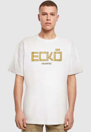 T-shirt en coton blanc featuring des lettres en blocs "ECKŌ" en jaune et "UNLIMITED" en plus petit en dessous. Coupe boxy, décontractée avec des manches courtes.