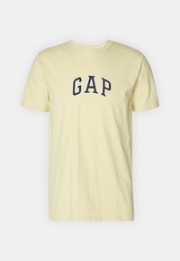 Světlé žluté bavlněné tričko s krátkými rukávy a kulatým výstřihem, na prsou uprostřed s tmavě modrým logem "GAP".
