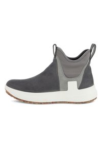 Zapato gris sin cordones hecho de ante y tela, con una suela blanca texturizada que presenta un patrón de manchas multicolores y una lengüeta en la parte trasera.